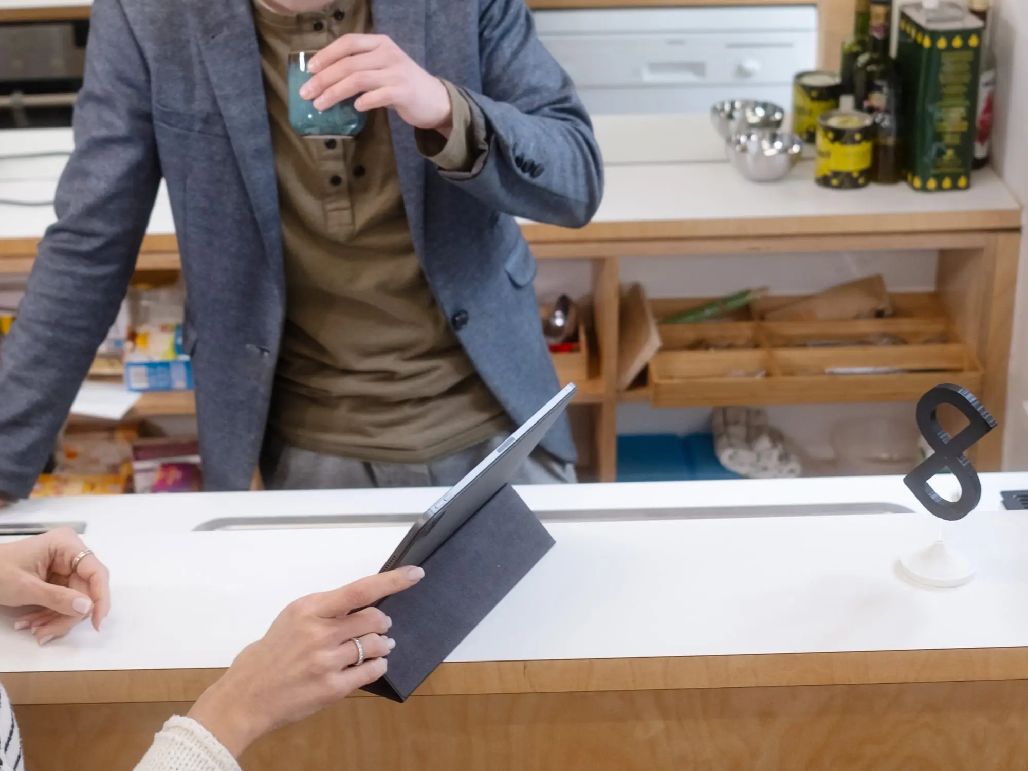 Moody shot of the kitchen bar at the pagestrip office, showing a designer presenting an idea on an iPad to a co-worker who's having a coffee.